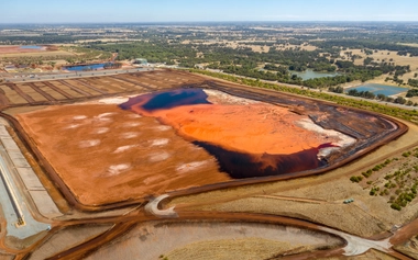 Mine tailings facility with orange and dark mineral areas surrounded by open land, showing material that can be repurposed into critical minerals and low‑carbon products.