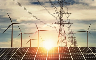 Solar panels and wind turbines with power lines at sunset