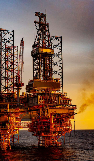 Offshore oil and gas platform at sunset with drilling rigs