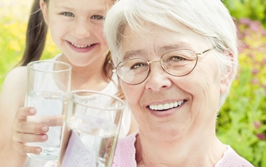Grandmother and grandaughter holding a glass of water