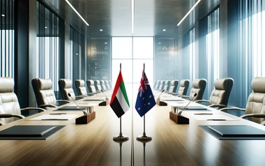 Modern conference room with UAE and Australian flags on a table, surrounded by leather chairs, microphones, and notebooks