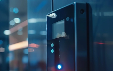 Close-up of an electronic access control panel with illuminated lights in a modern office hallway
