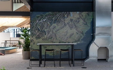 High table with stools in front of a large wall map inside workspace