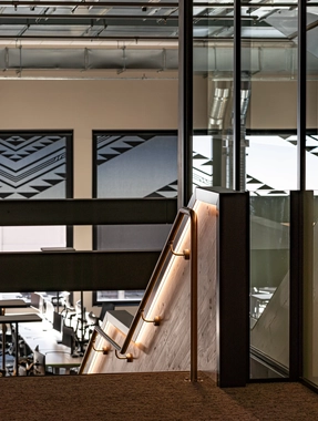Staircase with wood rail next to glass wall inside an office