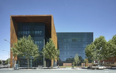 Contemporary urban building with glass facade and framed entry along a tree lined street