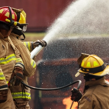Firefighters direct a hose stream toward active flames during a fire