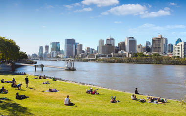 Scenic view of Brisbane city buildings with people enjoying the park and a river