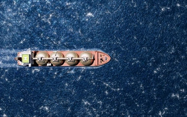 Aerial view of a cargo ship with spherical tanks sailing through blue water