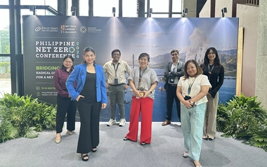 Group posing with an award in front of a conference display wall.