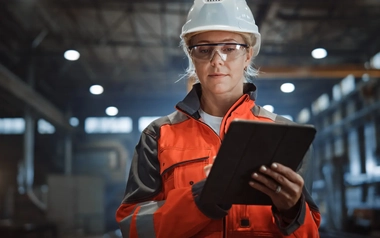 Professional Heavy Industry Engineer Worker Wearing Safety Uniform and Hard Hat Uses Tablet Computer.