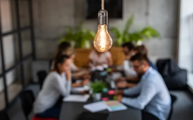 light bulb in a meeting room with employees