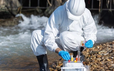 person collecting water samples wearing protective gear