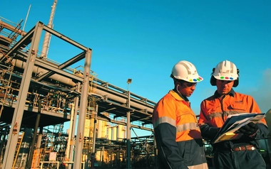Two field workers with complete safety equipment discussing