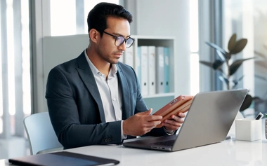 Businessman analyzing data on a tablet and laptop