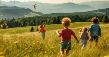 Children playing in an open field with kites and wind turbines in background