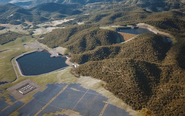 Aerial view of two reservoirs and a solar farm among forested hills.