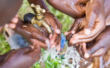Children washing their hands at an outdoor water tap