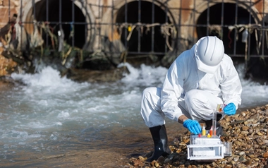 person collecting water samples in protective gear