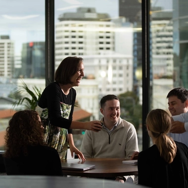 People gathered around a table in a meeting room with large windows