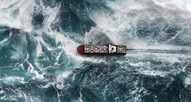 Cargo ship sailing along big waves