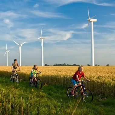 Children riding bicycle around a windfarm turbine