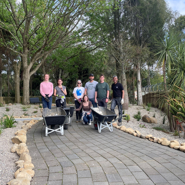 Group of people with wheelbarrows on a landscaped garden path outdoors