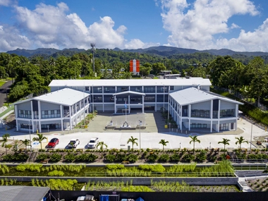 Bâtiment institutionnel moderne avec design durable, façade vitrée et aménagement écologique, situé dans un environnement tropical verdoyant.