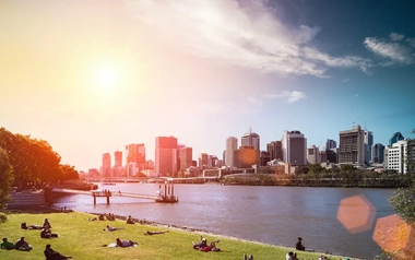 people relaxing on grass with tall buildings view during sunset