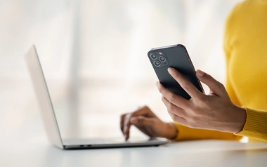  person holding a smartphone and using a laptop