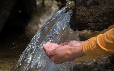 hands under a stream of water flowing