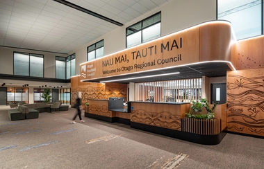 Reception desk with overhead signage and seating in a large lobby