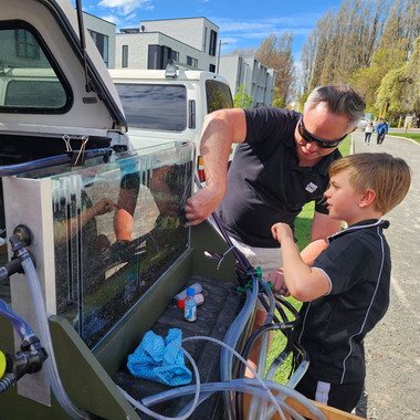 Adult and child working on a water experiment beside a vehicle