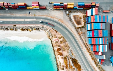 AdobeStock_551792303_Shipping-containers-at-Fremantle-Port-with-white-sandy-beach-and-clear-blue-sea