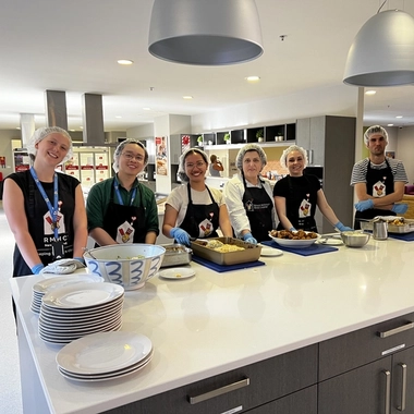 Volunteers in aprons preparing and serving food in a kitchen