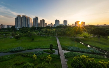 Singapore skyline with green park at sunset, highlighting land-use planning and sustainable waste management solutions.
