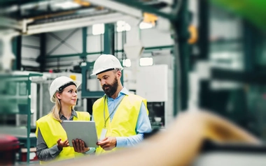 A portrait of an industrial man and woman engineer with tablet in a factory.