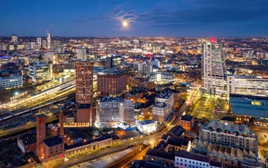 Aerial view of a cityscape at dusk featuring illuminated buildings