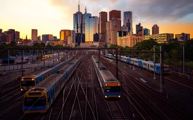 A multi‑track rail corridor with an Australian city skyline at sunset, representing digital and interconnected rail infrastructure.