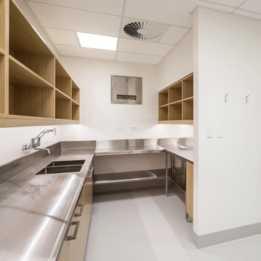 Clinical preparation room with stainless steel countertops, shelving, and bright, sterile finishes.