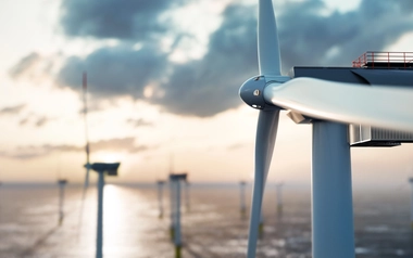 Offshore wind turbine above the sea with other turbines in the background.