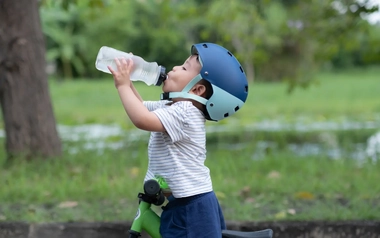 Boy on bike wearing helmet drinks from water bottle