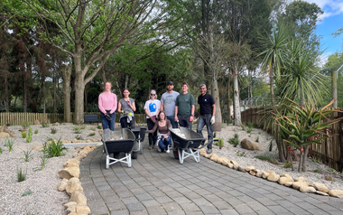 Group standing with wheelbarrows in a landscaped garden area