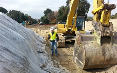 Field professional oversees environmental remediation activities alongside heavy equipment