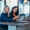 women talking while looking at a computer