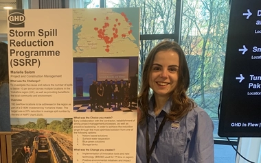 Marielle Salom standing beside a Storm Spill Reduction Programme presentation board at an event.