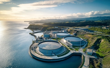 Aerial view of a coastal industrial water‑processing and desalination facility with circular treatment tanks.