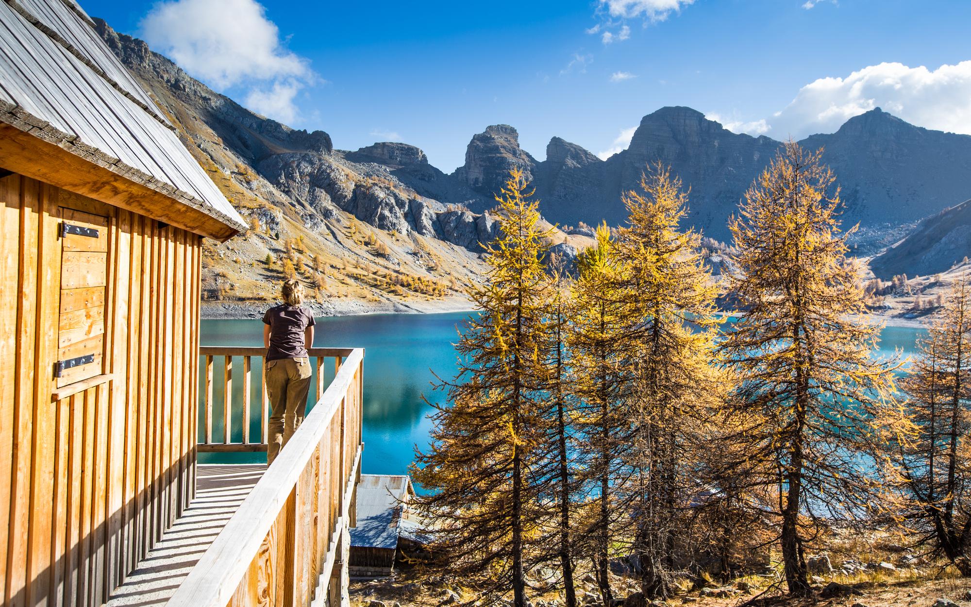 woman standing at the balcony by the lake and mountains