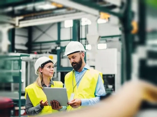 A portrait of an industrial man and woman engineer with tablet in a factory.