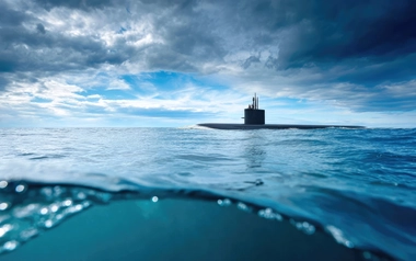 Submarine on the ocean surface under a cloudy sky.