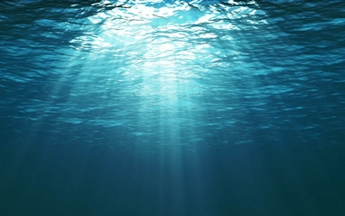 Underwater view of a vibrant blue ocean, with sunlight